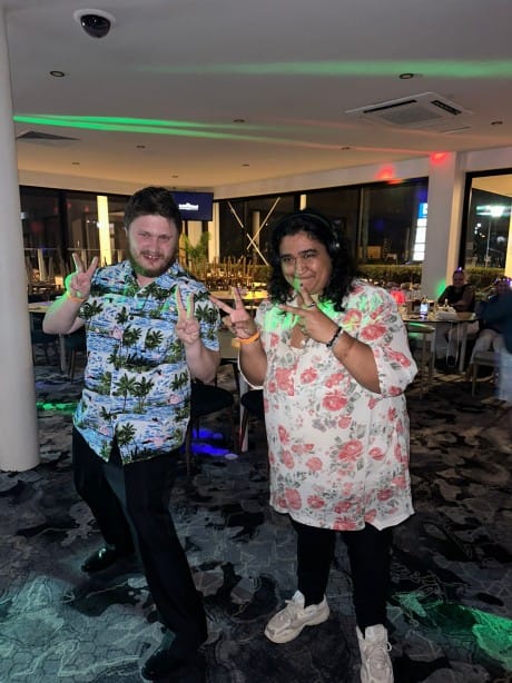 Two people smiling and doing the peace sign with their hands