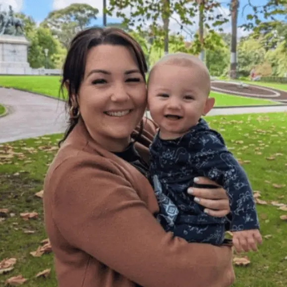 A woman smiling while holding a child