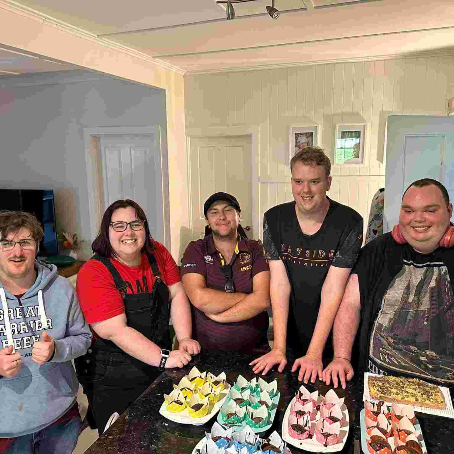 Group of people smiling while showing their baked cupcakes