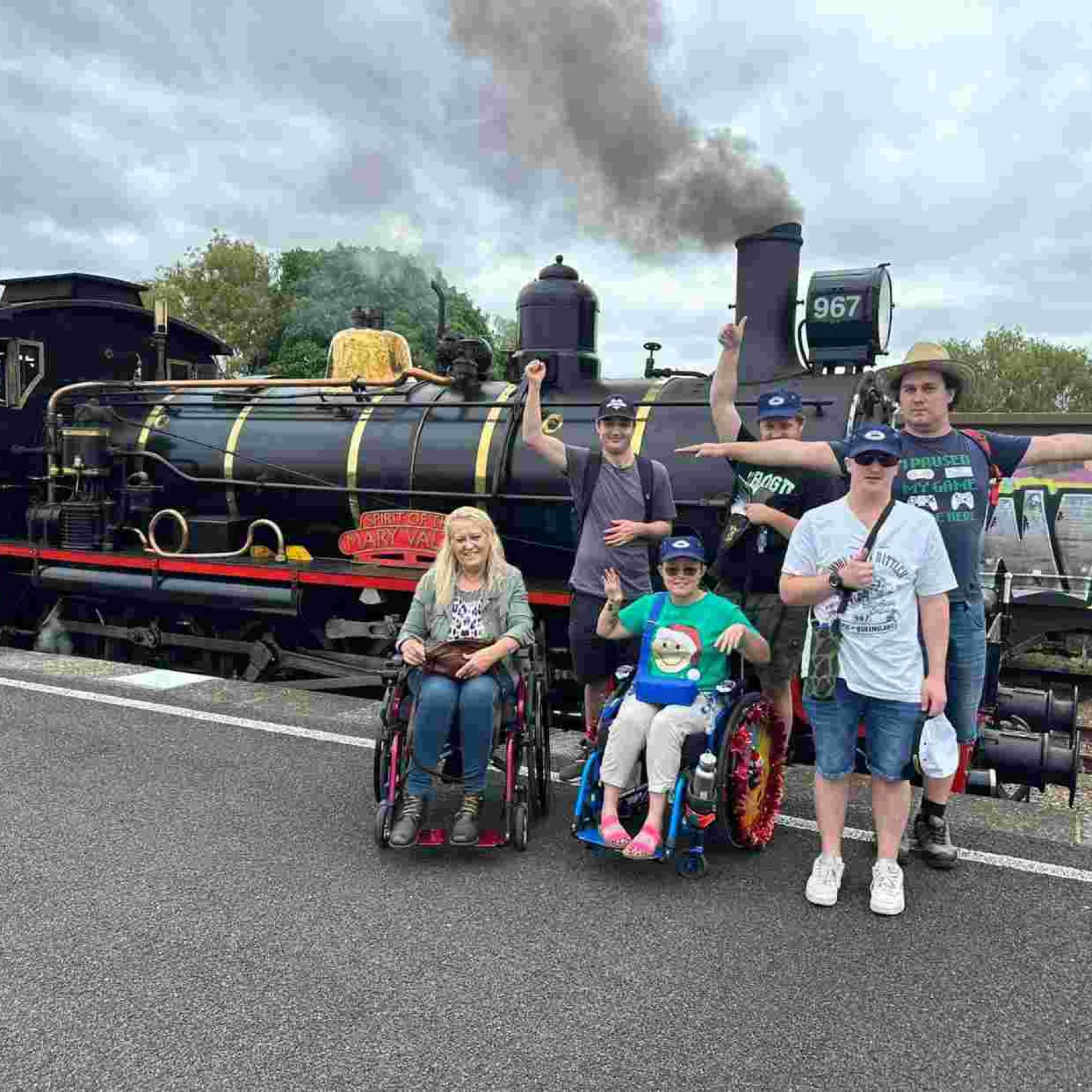 Group of people and disabled people in their wheelchair in front of a train