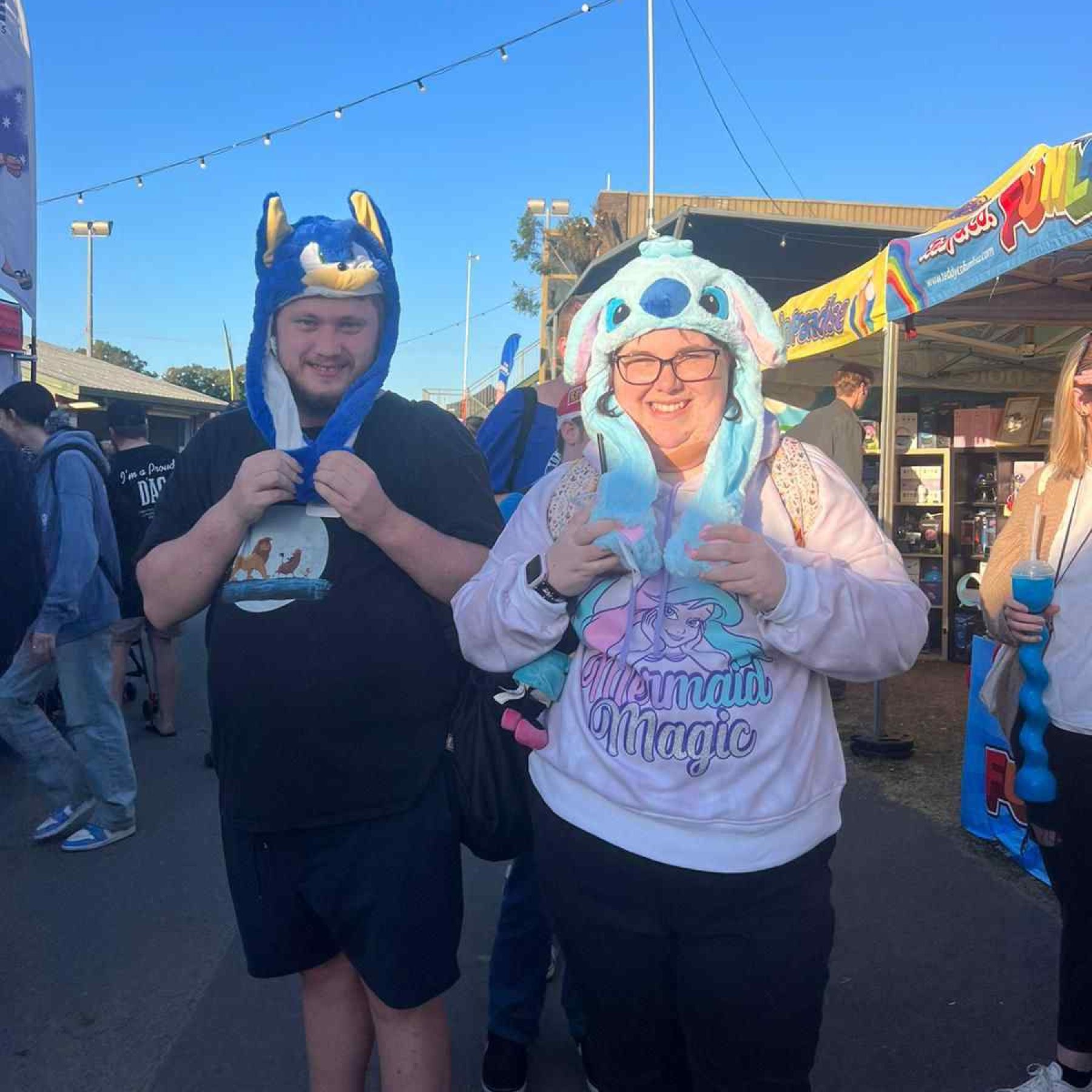 Two people smiling while holding their cartoon hat