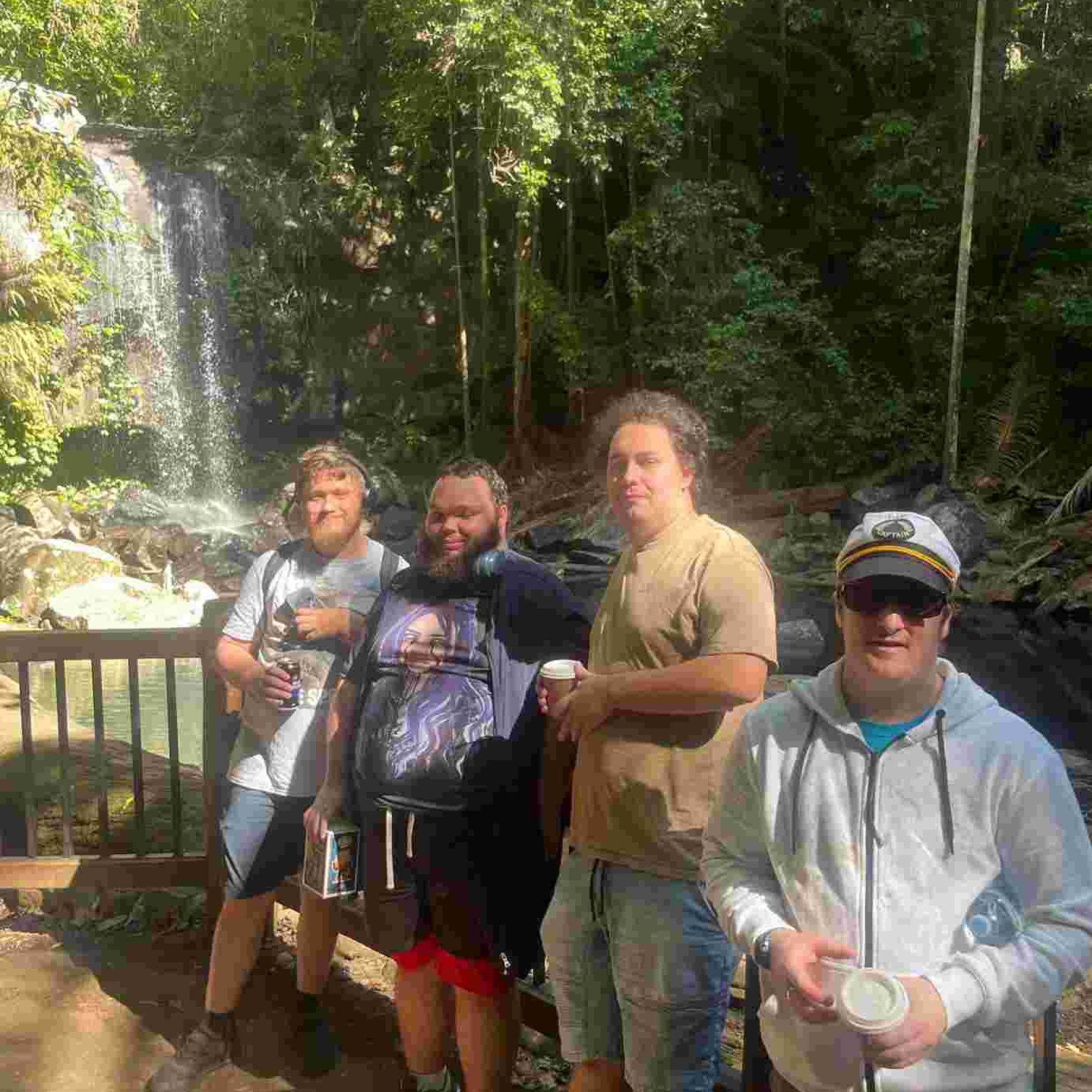 Group of men smiling while in front of a water fall