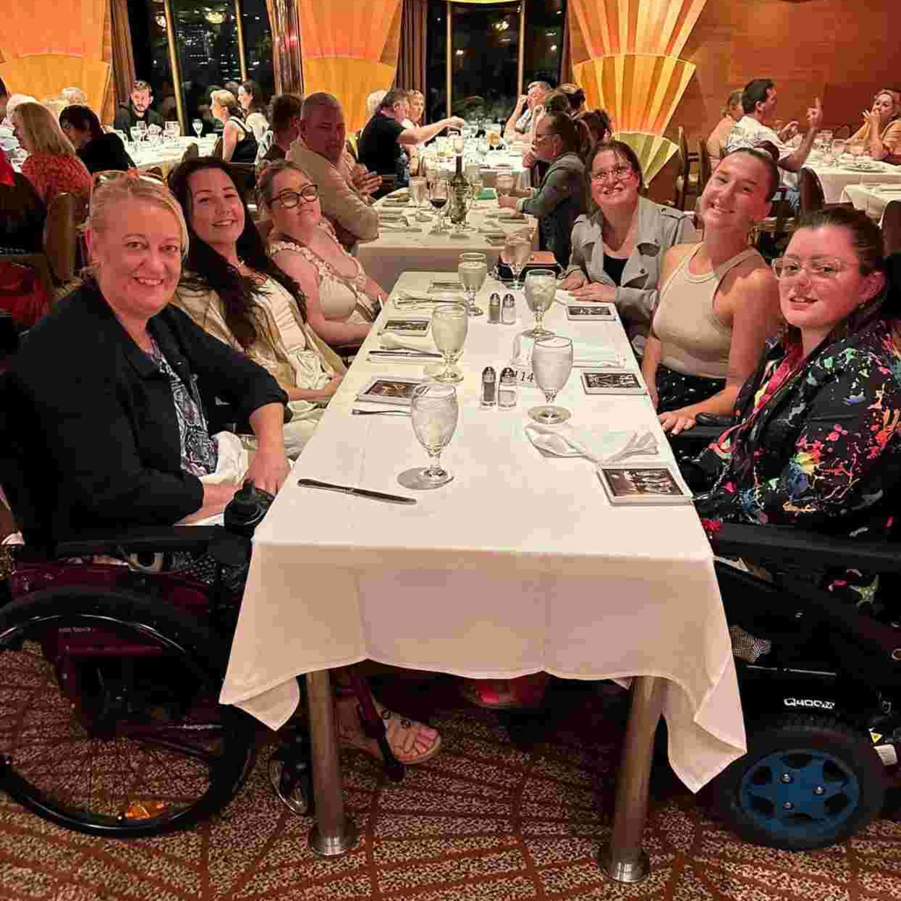 Group of people and disabled people in their wheelchair smiling inside the restaurant